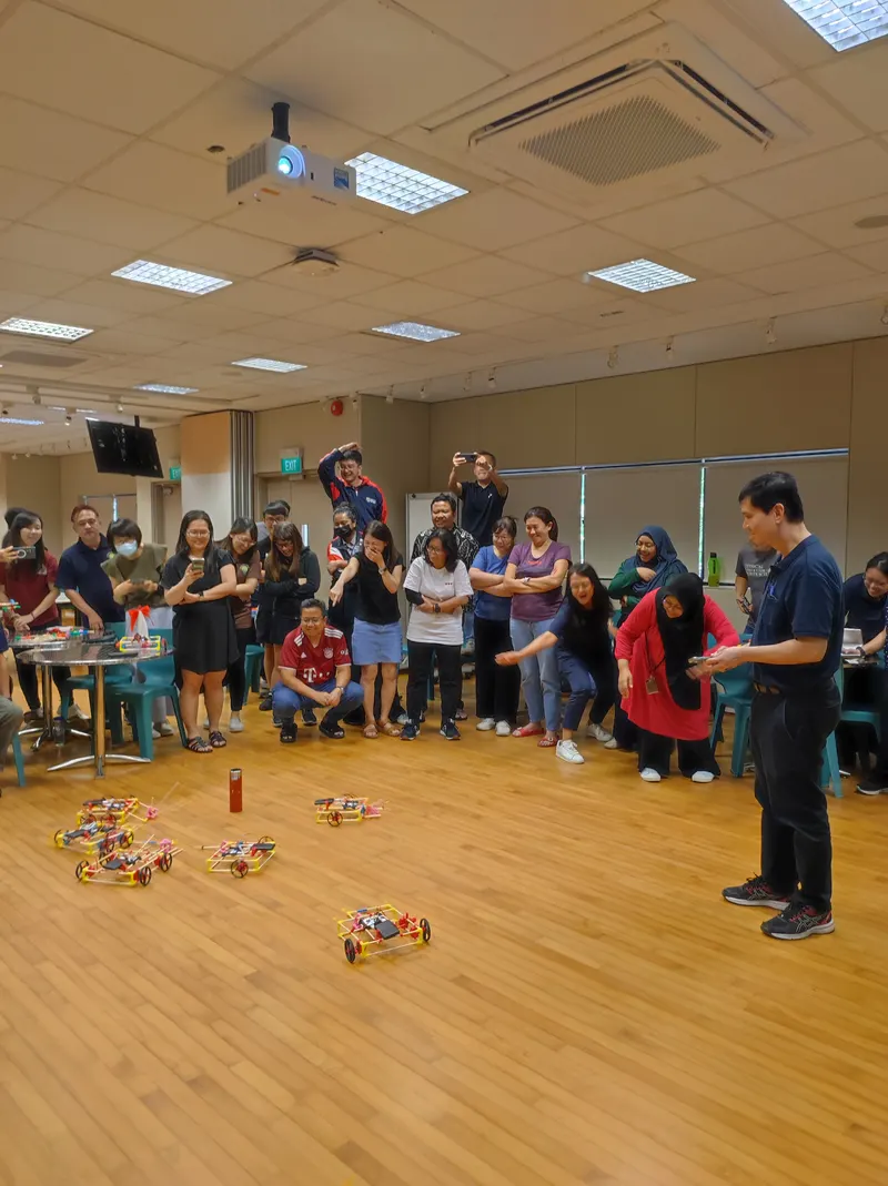 Blangah Rise Primary teachers racing robot cars across the hall floor