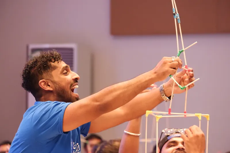 A teacher grinning as he holds up the top of his tower