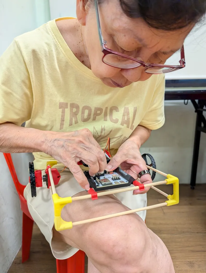 A senior fits a servo to her chopstick car at Braddell Heights