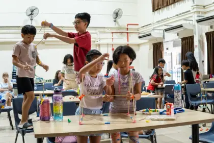 A helper guides two children through their build