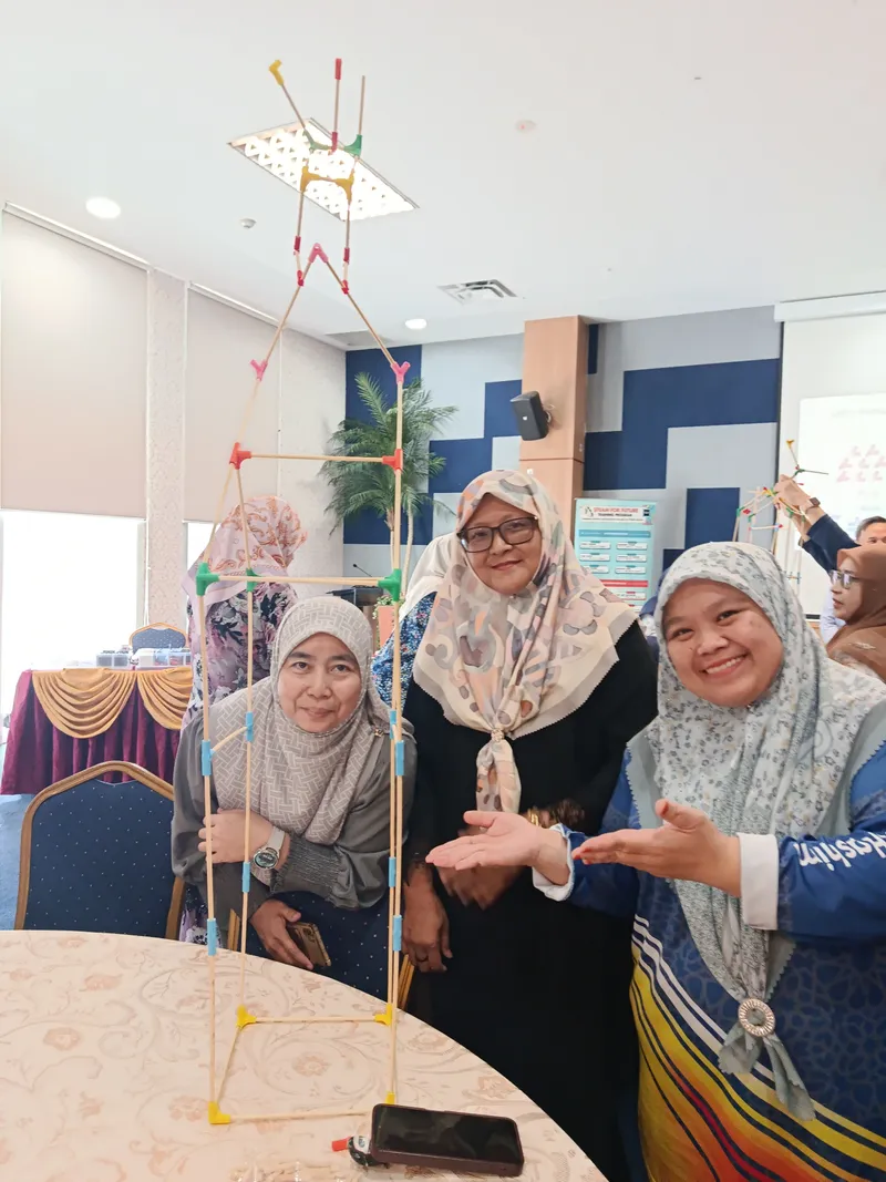 Teachers standing beside a tower that reaches the ceiling
